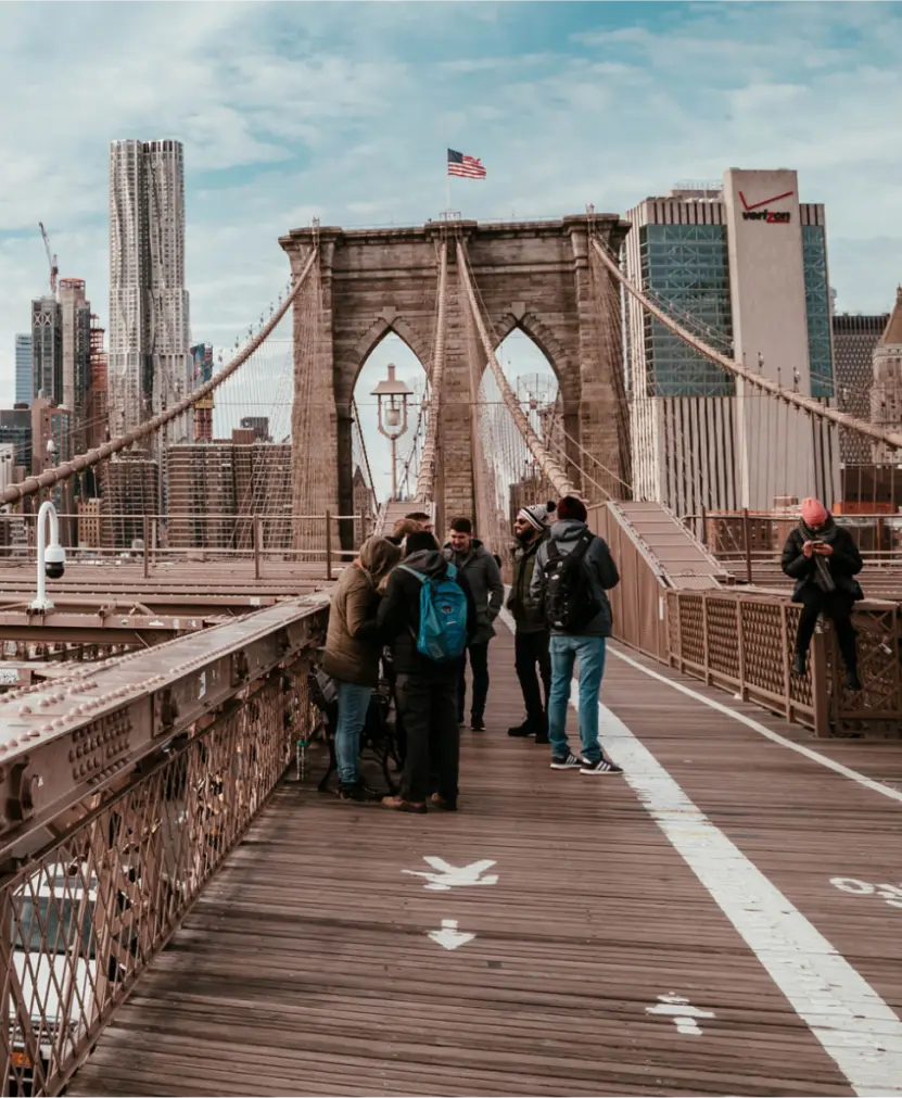 A group of people talk on the Brooklyn bridge.