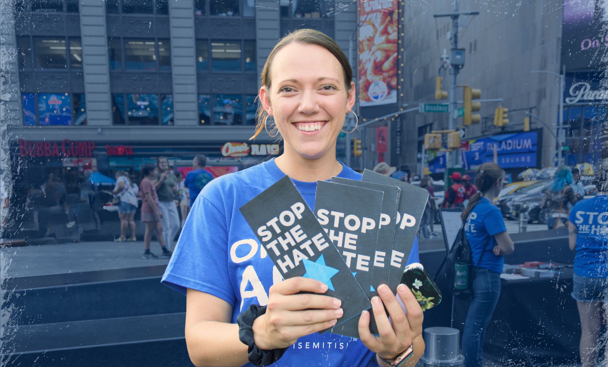 A staff member in a blue "Oppose Antisemitism" shirt passes out materials in Times Square New York